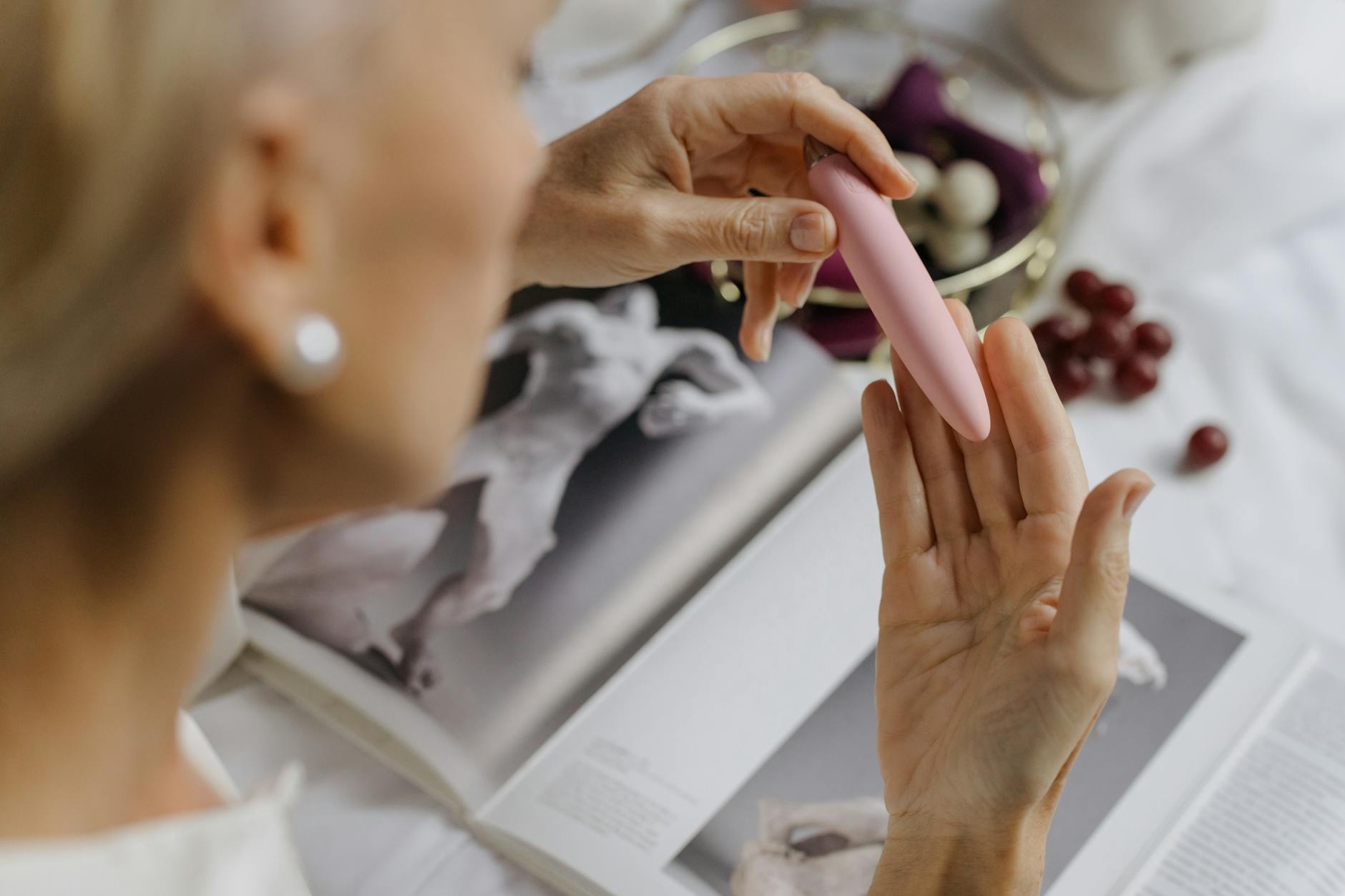 Zbliżenie dłoni trzymającej elegancki niebieski wibrator na purpurowym tle, wyrażające nowoczesną zmysłowość