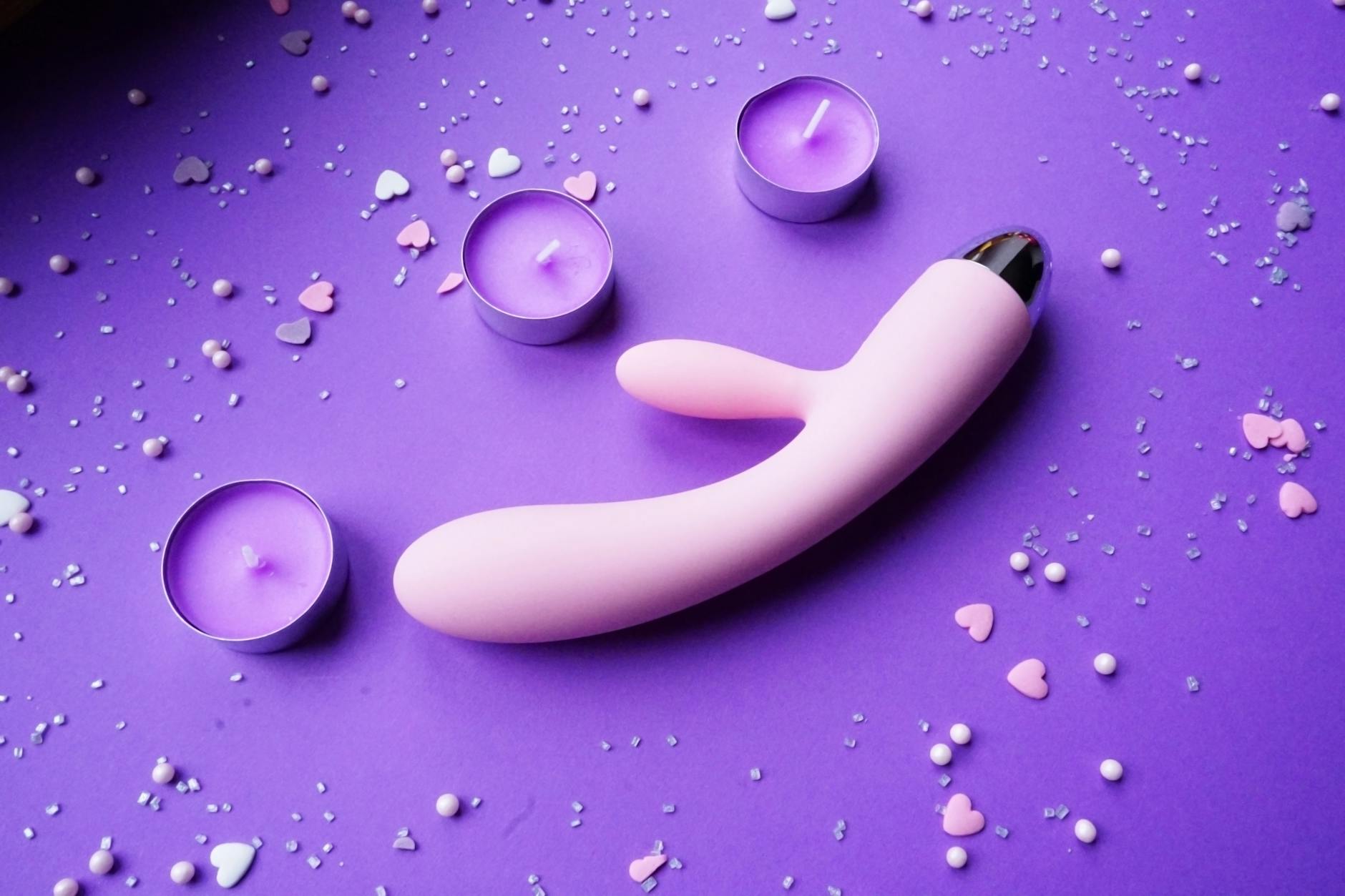 Różowy vibrator Lemon na fioletowym tle z serduszkami i świecami do romantycznego klimatu